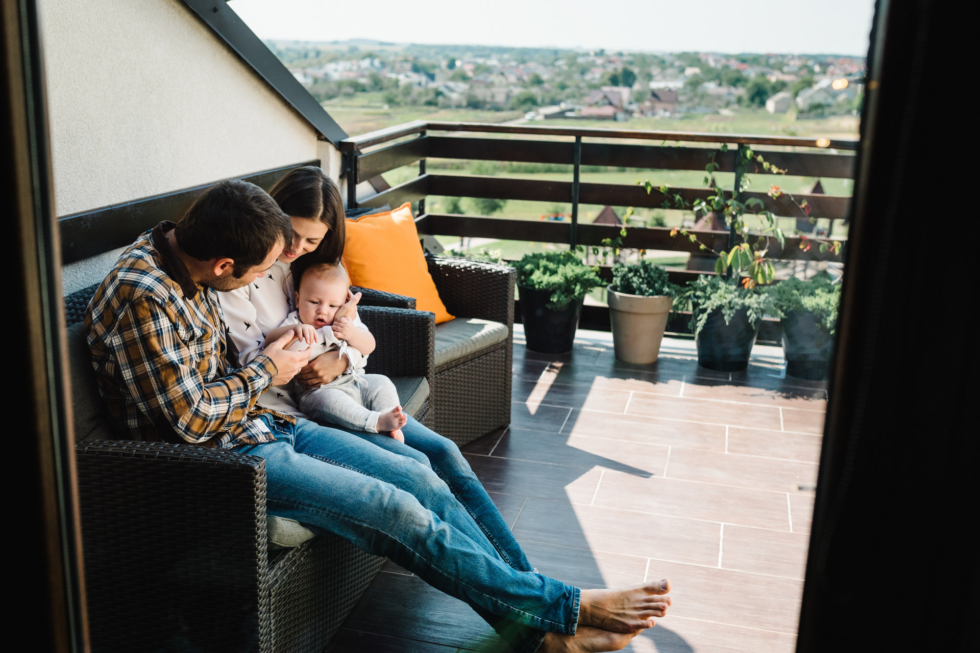 Portrait of young smiling family playing with son on the patio. Happy family, parenthood and people concept - mom, dad with baby boy near home. Spends time together on the terrace.